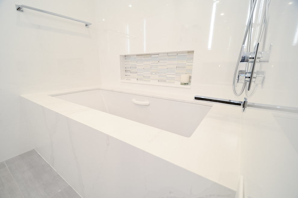 Large modern ensuite bathroom in New York with flat-panel cabinets, dark wood cabinets, an alcove bath, an alcove shower, a one-piece toilet, white tiles, glass tiles, white walls, porcelain flooring, a submerged sink, quartz worktops, grey floors, a hinged door and yellow worktops.