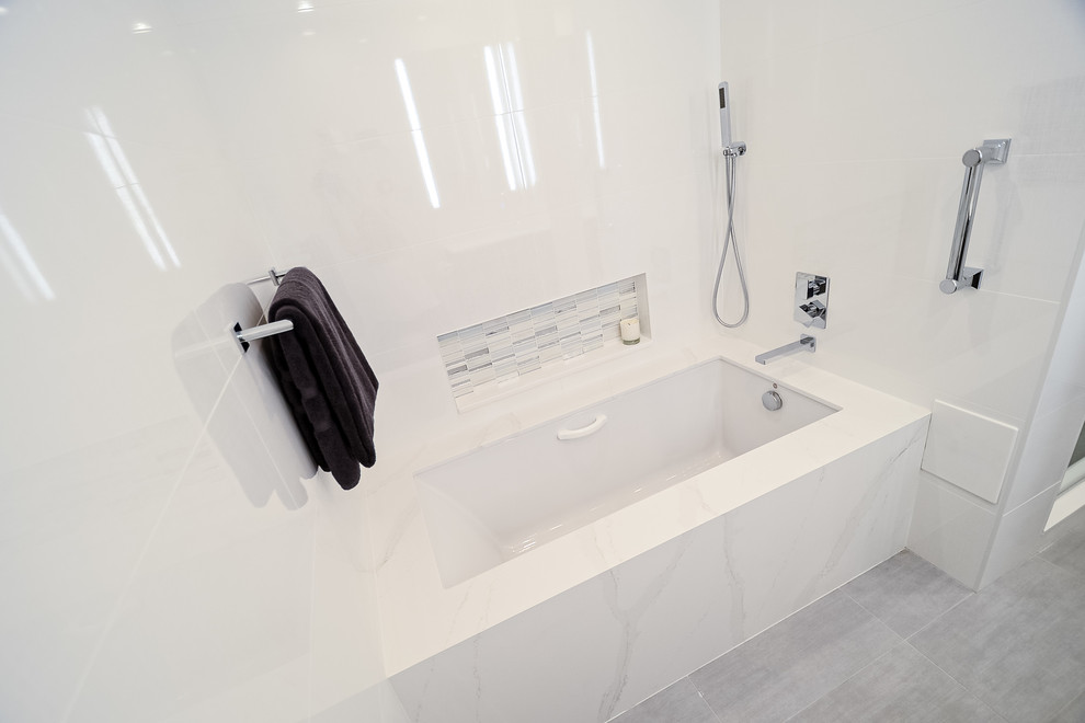 This is an example of a large modern ensuite bathroom in New York with flat-panel cabinets, dark wood cabinets, an alcove bath, an alcove shower, a one-piece toilet, white tiles, glass tiles, white walls, porcelain flooring, a submerged sink, quartz worktops, grey floors, a hinged door and yellow worktops.