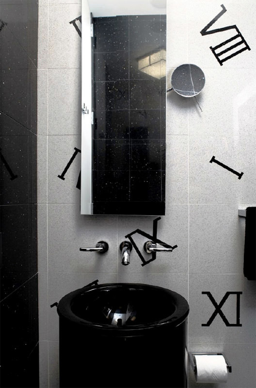 This is an example of a large modern ensuite bathroom in New York with flat-panel cabinets, a corner shower, a one-piece toilet, black and white tiles, ceramic tiles, white walls, ceramic flooring, a pedestal sink, black cabinets, granite worktops and white floors.