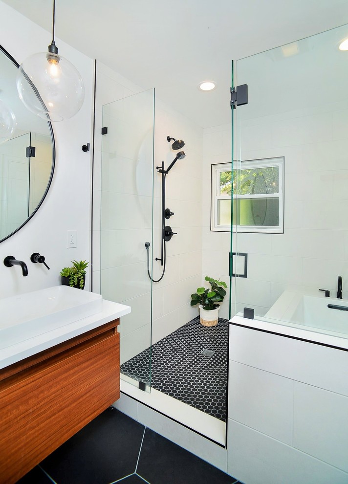 Design ideas for a modern wet room bathroom in Sacramento with flat-panel cabinets, medium wood cabinets, a submerged bath, a one-piece toilet, white tiles, porcelain tiles, white walls, porcelain flooring, a vessel sink, engineered stone worktops, black floors, a hinged door and white worktops.