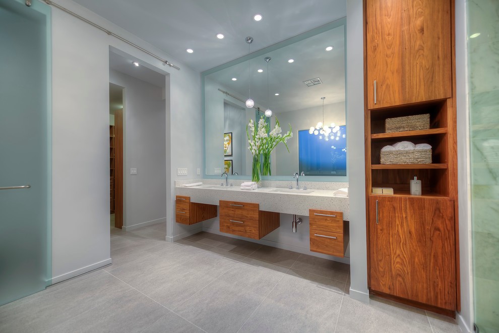 フェニックスにあるコンテンポラリースタイルのおしゃれなバスルーム (浴槽なし) (一体型シンク、フラットパネル扉のキャビネット、中間色木目調キャビネット、バリアフリー、グレーのタイル、グレーの壁) の写真