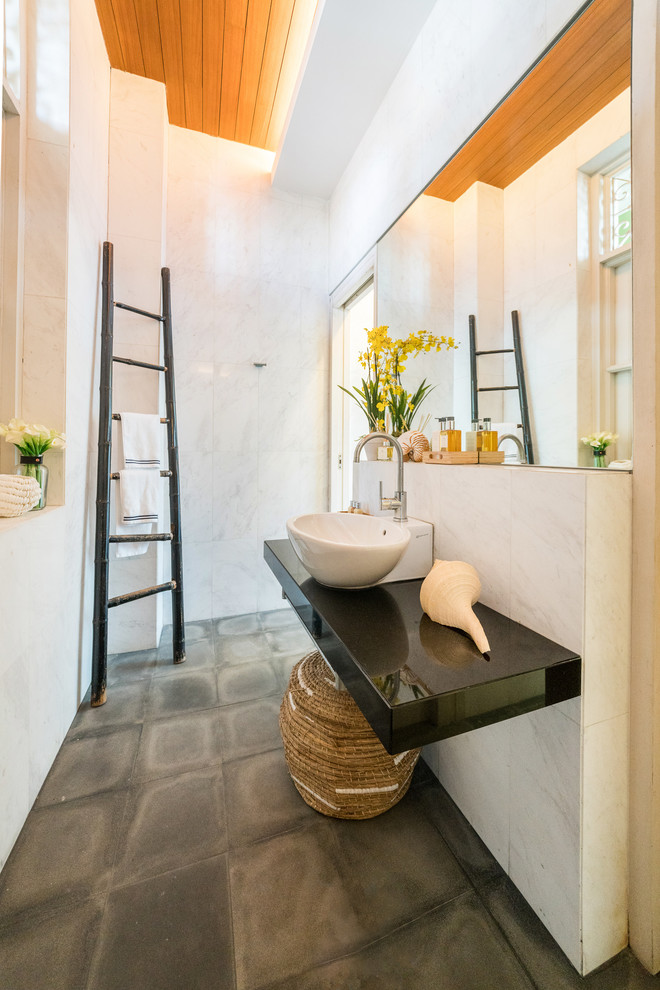 Стильный дизайн: ванная комната в восточном стиле с белыми стенами, бетонным полом, настольной раковиной, серым полом и черной столешницей - последний тренд
