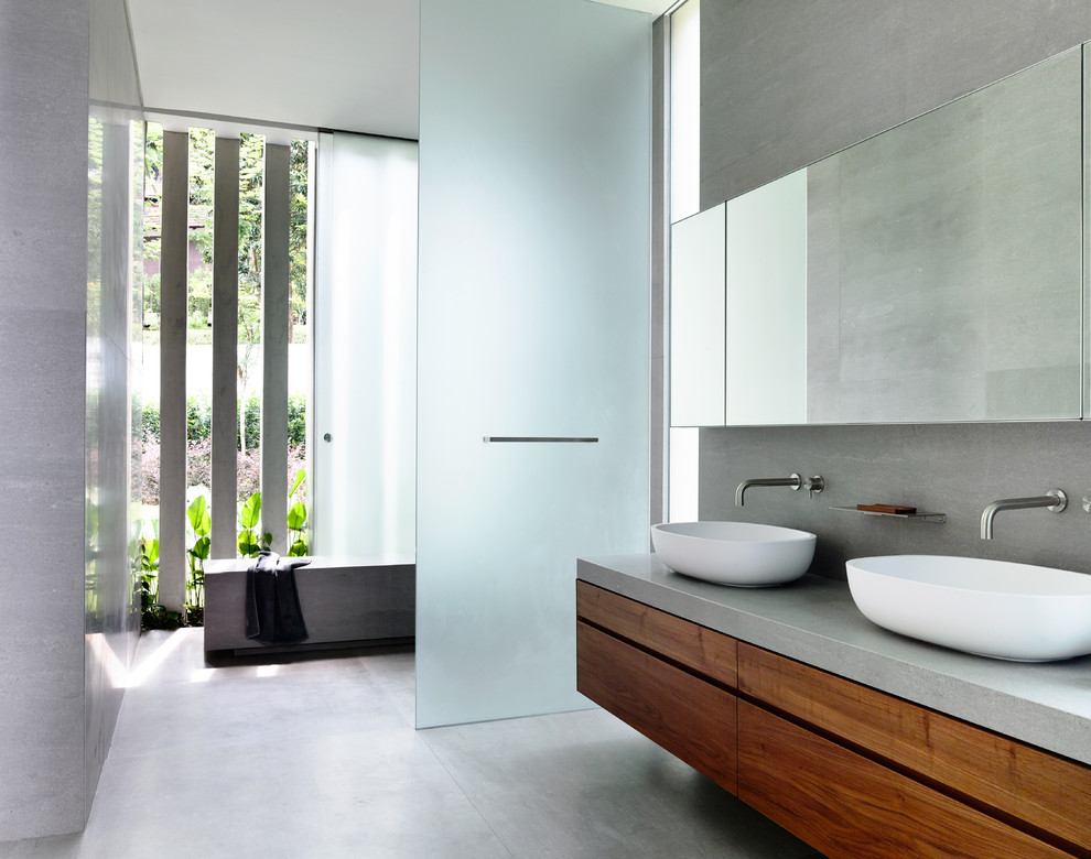 Imagen de cuarto de baño actual con armarios con paneles lisos, puertas de armario de madera oscura, paredes grises, lavabo sobreencimera, ducha abierta y encimeras grises