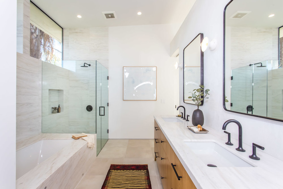 Inspiration for a contemporary ensuite bathroom in Los Angeles with flat-panel cabinets, medium wood cabinets, a submerged bath, a corner shower, beige tiles, white walls, a submerged sink, beige floors, a hinged door and white worktops.