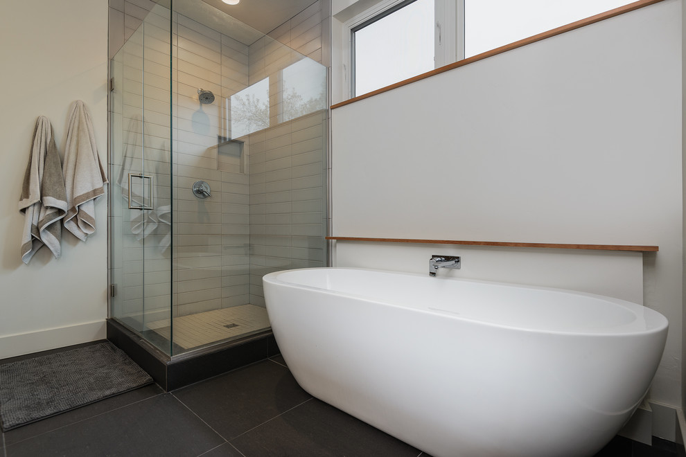 Photo of a medium sized contemporary ensuite bathroom in Other with flat-panel cabinets, light wood cabinets, a freestanding bath, a corner shower, a one-piece toilet, black tiles, porcelain tiles, cement flooring, a vessel sink and tiled worktops.