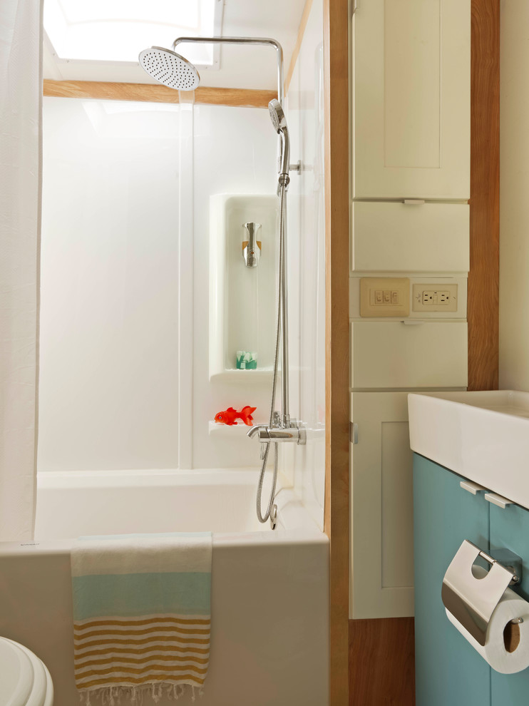 Immagine di una piccola stanza da bagno padronale eclettica con ante lisce, ante blu, vasca ad alcova, vasca/doccia, pareti bianche, parquet chiaro, lavabo rettangolare e doccia con tenda