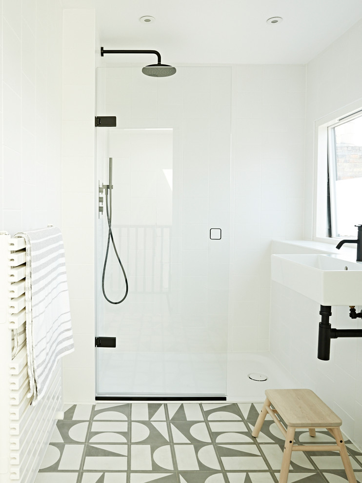 Modelo de cuarto de baño infantil escandinavo pequeño con paredes blancas, lavabo suspendido, suelo multicolor y ducha abierta