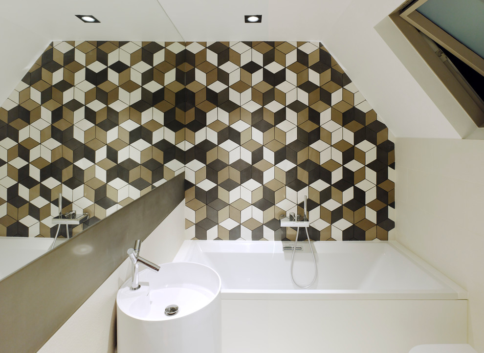 This is an example of a contemporary bathroom in London with a pedestal sink, a built-in bath, multi-coloured tiles, white walls and a feature wall.