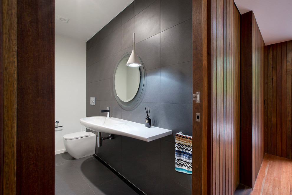 Esempio di una stanza da bagno minimalista con piastrelle grigie, piastrelle in pietra, doccia alcova, lavabo sospeso e pareti grigie