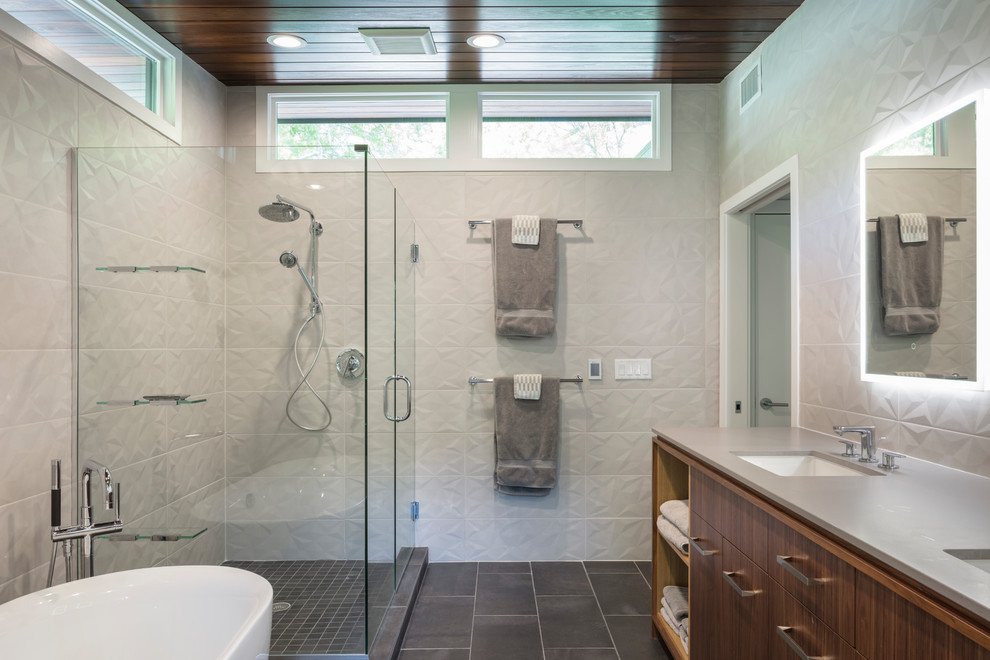 Mid-Century Badezimmer En Suite mit flächenbündigen Schrankfronten, dunklen Holzschränken, weißen Fliesen, weißer Wandfarbe, Unterbauwaschbecken, grauem Boden und Falttür-Duschabtrennung in Kansas City