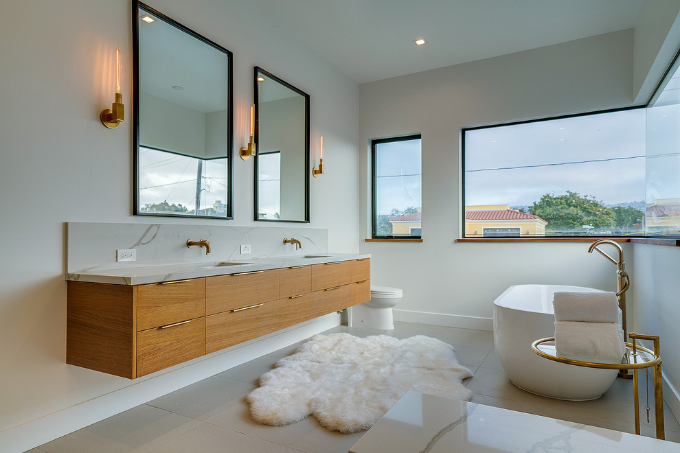 Aménagement d'une salle de bain contemporaine en bois brun avec un placard à porte plane, une baignoire indépendante, un mur blanc, un lavabo encastré, un sol gris et un plan de toilette blanc.
