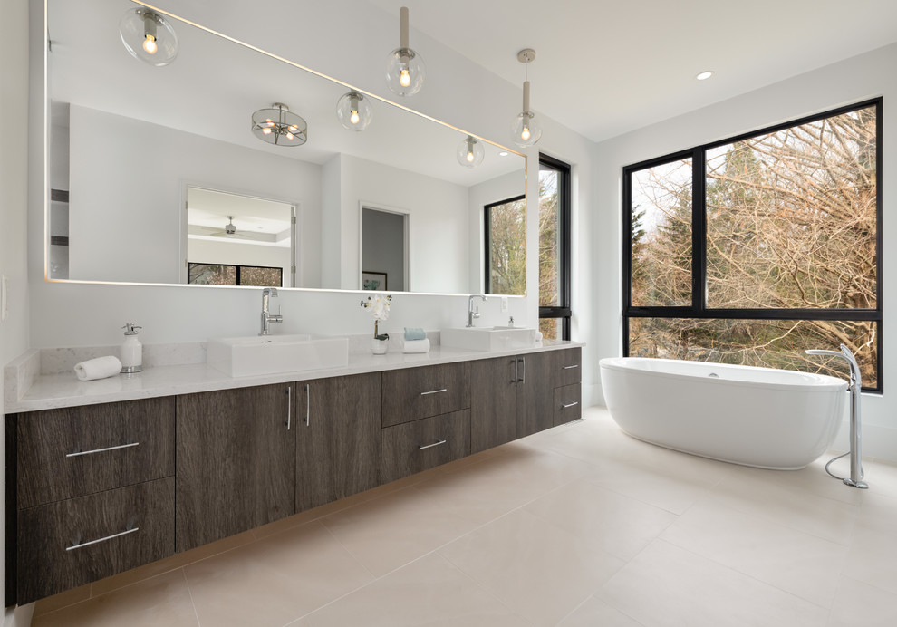 Идея дизайна: ванная комната в современном стиле с плоскими фасадами, серыми фасадами, отдельно стоящей ванной, белыми стенами, настольной раковиной, бежевым полом и белой столешницей