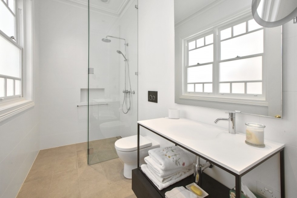 Immagine di una stanza da bagno padronale minimal di medie dimensioni con ante nere, doccia alcova, piastrelle beige e piastrelle in pietra