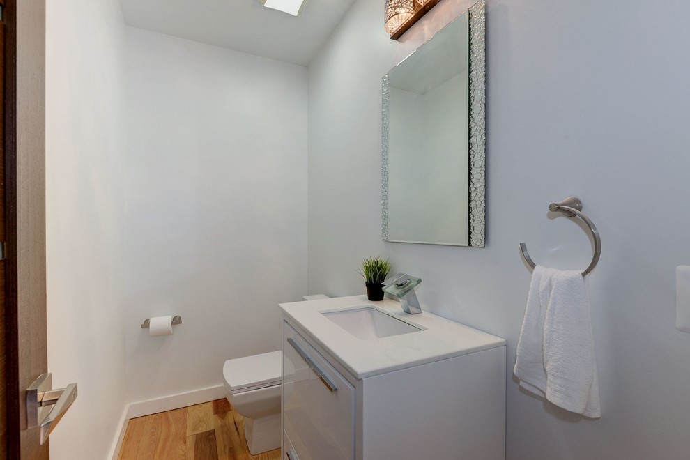 Свежая идея для дизайна: ванная комната среднего размера в современном стиле с плоскими фасадами, белыми фасадами, раздельным унитазом, белыми стенами, светлым паркетным полом, душевой кабиной, врезной раковиной и столешницей из искусственного камня - отличное фото интерьера