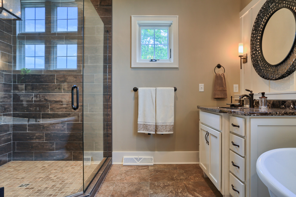 Modelo de cuarto de baño principal campestre grande con puertas de armario blancas, encimera de granito, ducha esquinera, baldosas y/o azulejos marrones y paredes beige