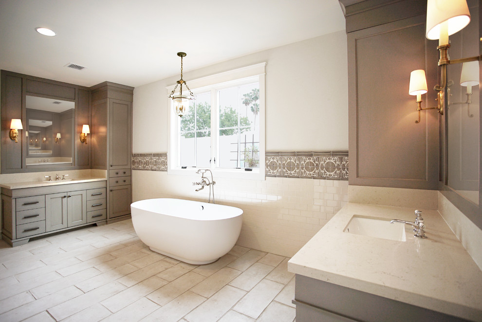 Inspiration for a large timeless master beige tile, brown tile and porcelain tile porcelain tile and beige floor freestanding bathtub remodel in Phoenix with recessed-panel cabinets, gray cabinets, beige walls, an undermount sink and quartzite countertops