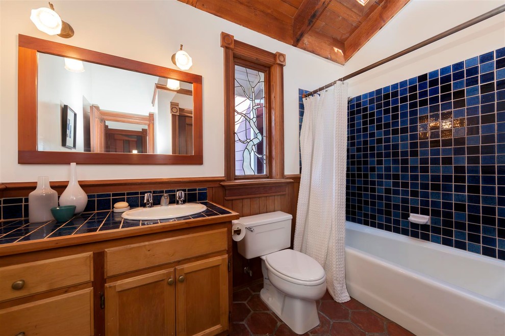 サンフランシスコにあるトランジショナルスタイルのおしゃれな浴室 (オーバーカウンターシンク、シャワー付き浴槽	、タイルの洗面台、シャワーカーテン、青い洗面カウンター) の写真