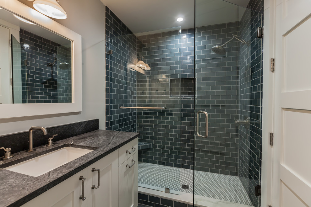 Example of a cottage 3/4 blue tile and ceramic tile limestone floor and gray floor doorless shower design in San Diego with shaker cabinets, white cabinets, a one-piece toilet, gray walls, an undermount sink, soapstone countertops, a hinged shower door and gray countertops