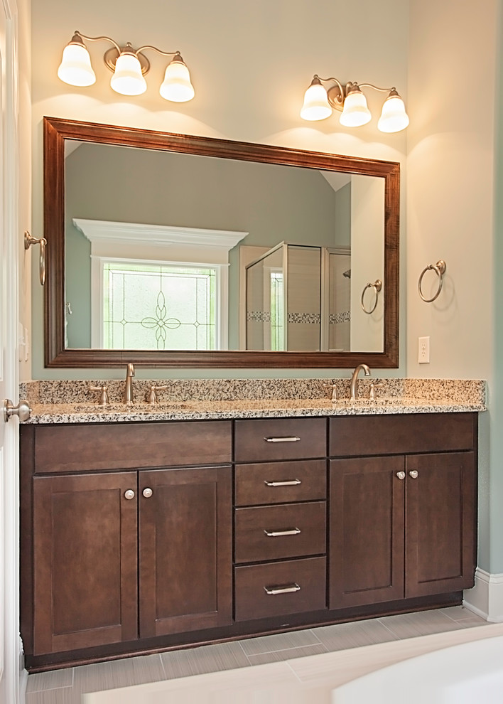 Inredning av ett klassiskt en-suite badrum, med ett undermonterad handfat, bruna skåp, granitbänkskiva, en hörndusch och klinkergolv i porslin