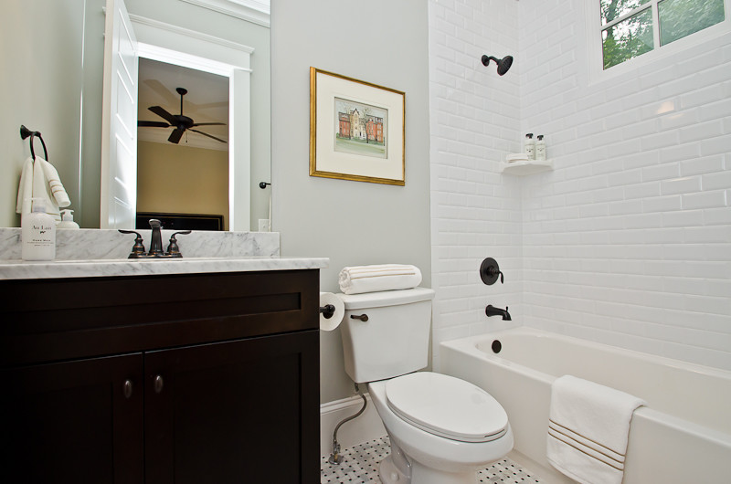 Cette photo montre une salle de bain craftsman en bois foncé de taille moyenne avec un lavabo encastré, un placard en trompe-l'oeil, un plan de toilette en granite, une baignoire en alcôve, un combiné douche/baignoire, WC à poser, un carrelage blanc, un carrelage métro, un mur gris et un sol en carrelage de céramique.