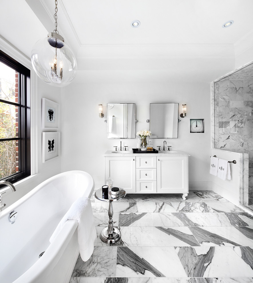 Klassisk inredning av ett badrum, med ett undermonterad handfat, luckor med infälld panel, vita skåp, ett fristående badkar och en dusch i en alkov