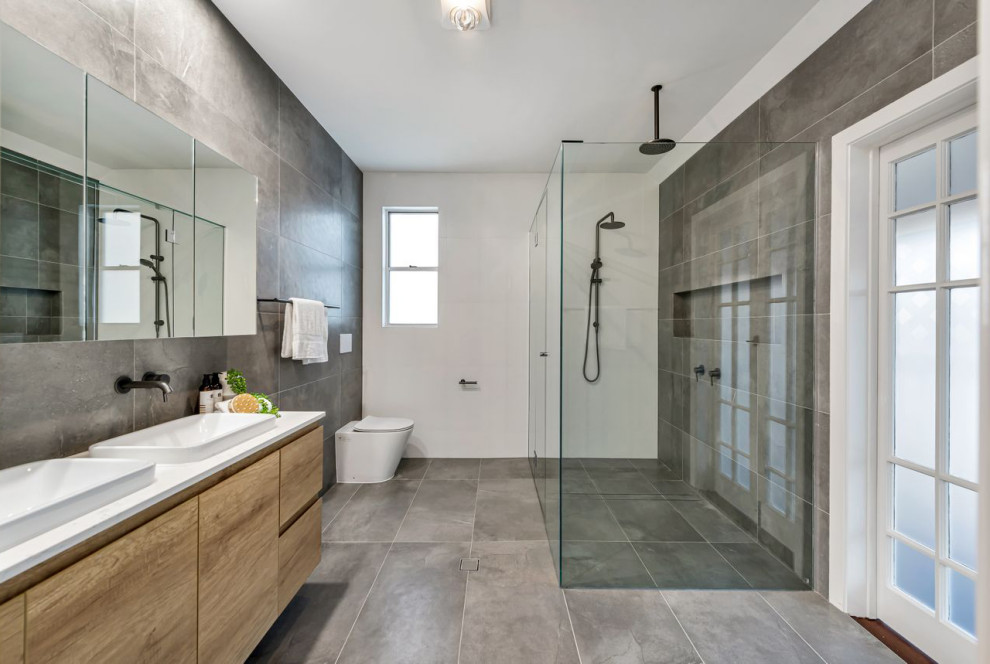 Idéer för ett mellanstort modernt vit badrum med dusch, med släta luckor, beige skåp, en hörndusch, en vägghängd toalettstol, grå kakel, porslinskakel, vita väggar, klinkergolv i porslin, ett fristående handfat, grått golv och dusch med gångjärnsdörr