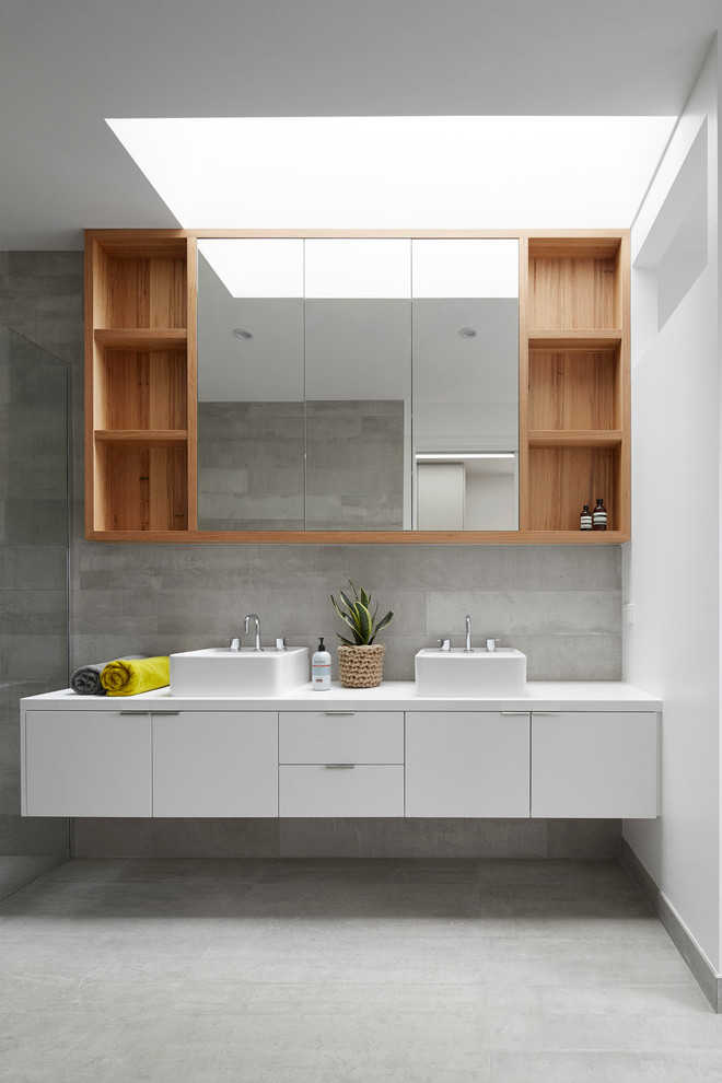 Идея дизайна: главная ванная комната среднего размера в скандинавском стиле с консольной раковиной, плоскими фасадами, белыми фасадами, столешницей из искусственного кварца, серой плиткой, каменной плиткой, серыми стенами и бетонным полом
