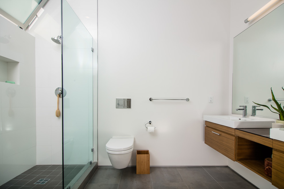 Idées déco pour une douche en alcôve principale moderne en bois brun avec une vasque, un placard à porte plane, WC suspendus, un carrelage gris, des carreaux de céramique, un mur blanc et un sol en carrelage de porcelaine.