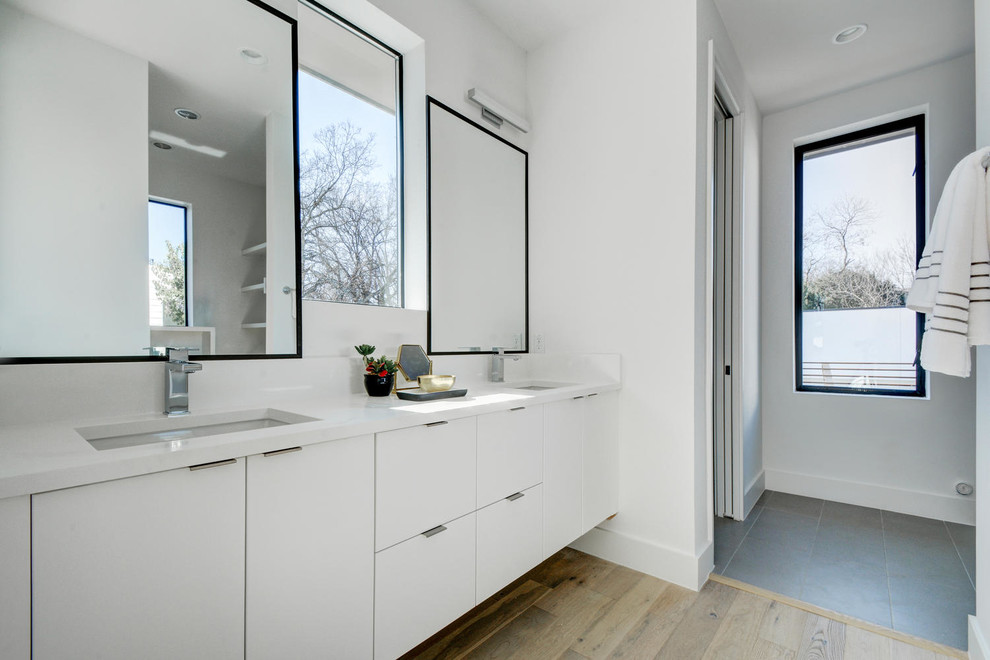 Mittelgroßes Modernes Badezimmer En Suite mit flächenbündigen Schrankfronten, weißen Schränken, Nasszelle, weißer Wandfarbe, hellem Holzboden und Unterbauwaschbecken in Austin