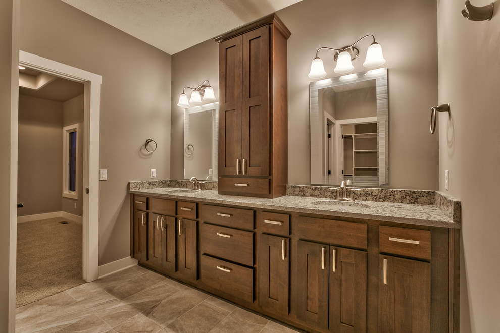 Example of a mid-sized tuscan master gray tile and ceramic tile ceramic tile doorless shower design in Omaha with an undermount sink, recessed-panel cabinets, medium tone wood cabinets, granite countertops and gray walls