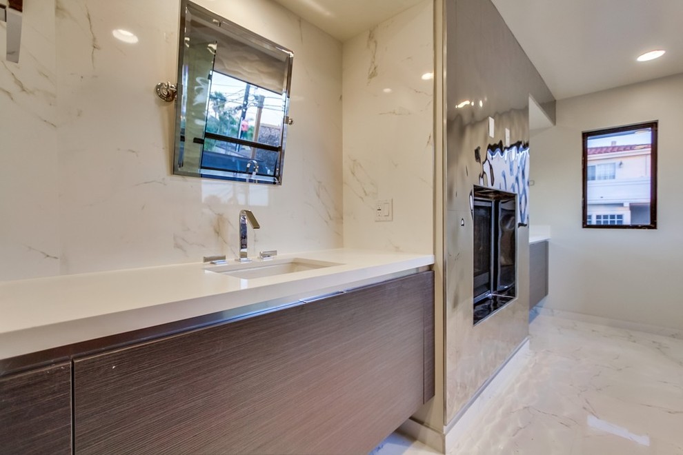 Esempio di una grande stanza da bagno padronale minimal con lavabo sottopiano, ante lisce, ante in legno chiaro, top in quarzo composito, vasca/doccia, WC monopezzo, piastrelle a specchio, pareti bianche e pavimento in marmo