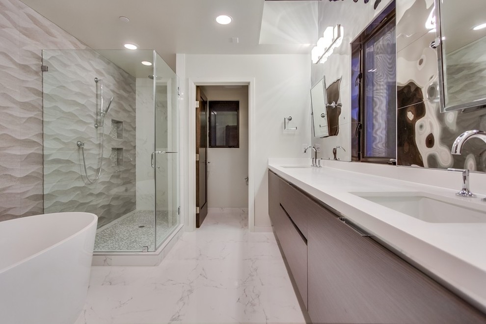 ロサンゼルスにある広いコンテンポラリースタイルのおしゃれなマスターバスルーム (アンダーカウンター洗面器、フラットパネル扉のキャビネット、淡色木目調キャビネット、クオーツストーンの洗面台、置き型浴槽、シャワー付き浴槽	、一体型トイレ	、ミラータイル、白い壁、大理石の床) の写真