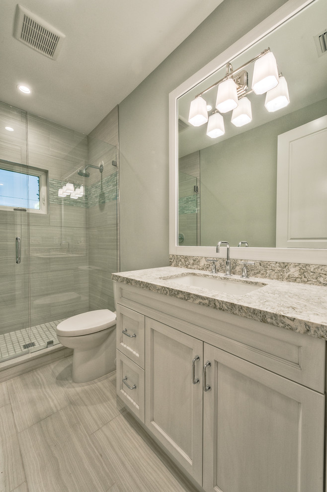 Doorless shower - mid-sized kids' gray tile and ceramic tile ceramic tile and gray floor doorless shower idea with recessed-panel cabinets, gray cabinets, a two-piece toilet, gray walls, an undermount sink, granite countertops and a hinged shower door