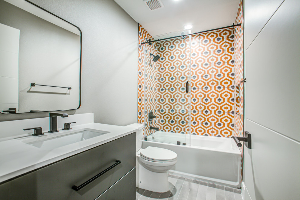 На фото: детская ванная комната в стиле неоклассика (современная классика) с плоскими фасадами, серыми фасадами, накладной ванной, раздельным унитазом, оранжевой плиткой, керамогранитной плиткой, серыми стенами, полом из керамической плитки, врезной раковиной, столешницей из искусственного кварца, серым полом, душем с раздвижными дверями, белой столешницей, тумбой под одну раковину и встроенной тумбой с
