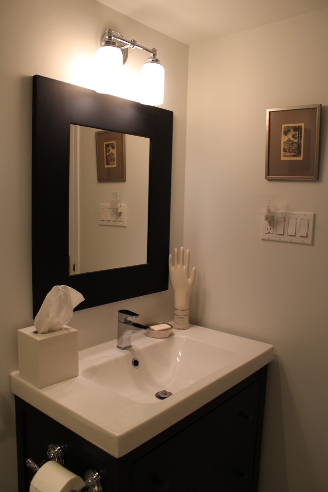 Esempio di un piccolo bagno di servizio minimal con ante lisce, ante nere, pareti bianche, pavimento con piastrelle a mosaico, WC monopezzo, lavabo integrato e top in laminato