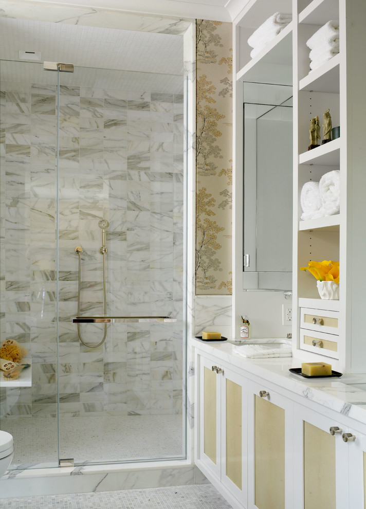 Modelo de cuarto de baño principal, tradicional renovado, de tamaño medio, con lavabo bajoencimera, armarios con paneles empotrados, puertas de armario blancas, encimera de mármol, ducha empotrada, baldosas y/o azulejos blancos, baldosas y/o azulejos de piedra, paredes amarillas y suelo con mosaicos de baldosas