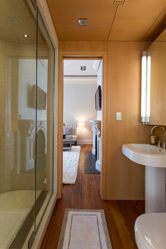 Exempel på ett litet klassiskt badrum med dusch, med ett piedestal handfat, släta luckor, skåp i ljust trä, en dusch i en alkov, en toalettstol med separat cisternkåpa, vit kakel, glaskakel, bruna väggar och mellanmörkt trägolv