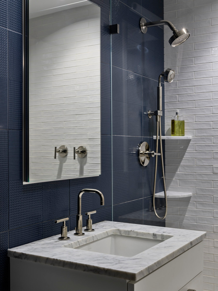На фото: ванная комната в стиле неоклассика (современная классика) с белыми фасадами, душем в нише, белой плиткой, плиткой кабанчик, синими стенами, душевой кабиной, врезной раковиной, мраморной столешницей, душем с распашными дверями и серой столешницей с