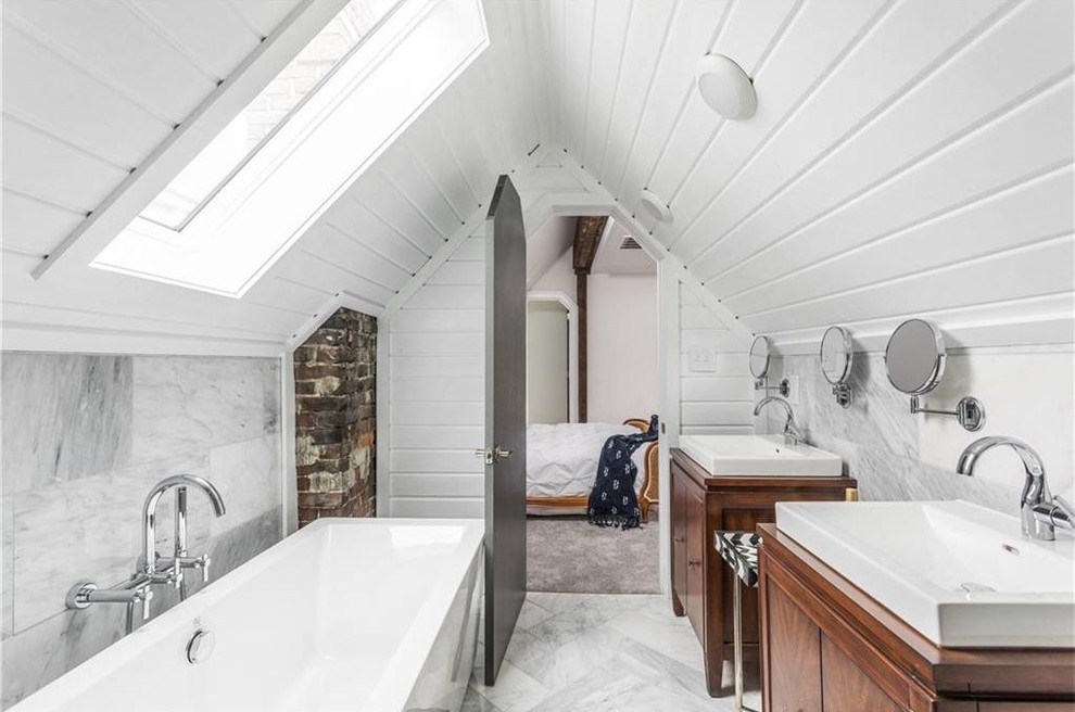 Klassisches Badezimmer mit dunklen Holzschränken, freistehender Badewanne, grauen Fliesen, weißer Wandfarbe und flächenbündigen Schrankfronten in Indianapolis