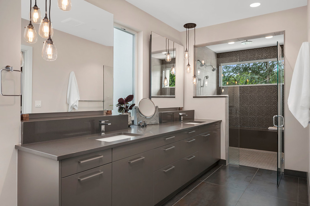 This is an example of a contemporary ensuite bathroom in Seattle with flat-panel cabinets, grey cabinets, an alcove shower, grey tiles, beige walls, a submerged sink, brown floors and a hinged door.