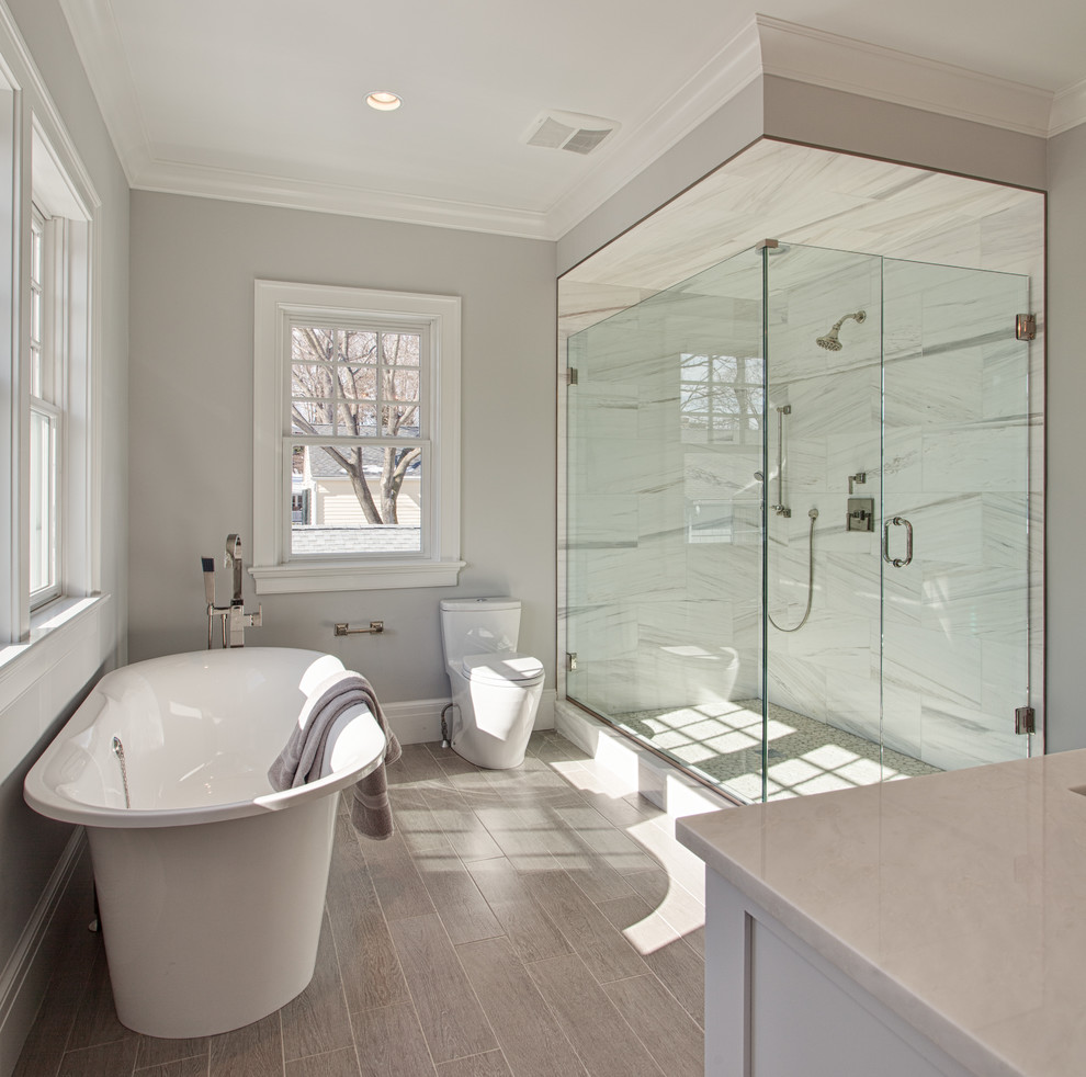 Large beach style master gray tile and stone tile ceramic tile and brown floor bathroom photo in Other with an undermount sink, recessed-panel cabinets, white cabinets, marble countertops, a one-piece toilet, gray walls and a hinged shower door