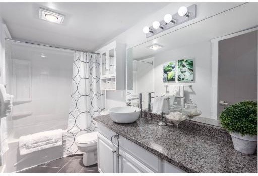 Bild på ett mellanstort funkis badrum med dusch, med luckor med upphöjd panel, vita skåp, ett badkar i en alkov, en dusch/badkar-kombination, en toalettstol med separat cisternkåpa, vita väggar, klinkergolv i porslin, ett fristående handfat och bänkskiva i terrazo