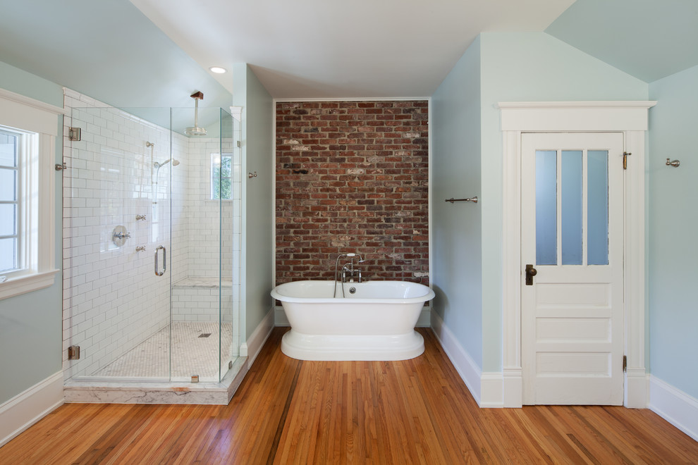 Inredning av ett amerikanskt en-suite badrum, med ett undermonterad handfat, släta luckor, vita skåp, marmorbänkskiva, ett fristående badkar, en öppen dusch, en toalettstol med separat cisternkåpa, vit kakel, tunnelbanekakel, gröna väggar och ljust trägolv