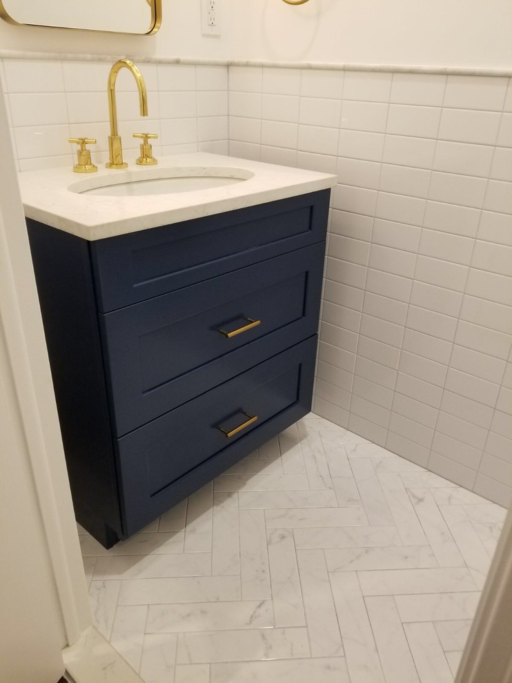 This is an example of a small contemporary shower room bathroom in New York with shaker cabinets, blue cabinets, a wall mounted toilet, white tiles, metro tiles, white walls, porcelain flooring, a submerged sink and engineered stone worktops.
