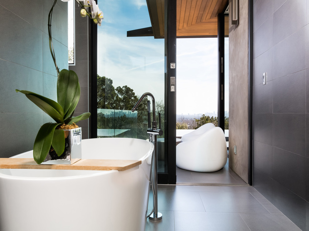 Modelo de cuarto de baño actual con bañera exenta, baldosas y/o azulejos grises, paredes grises y suelo gris