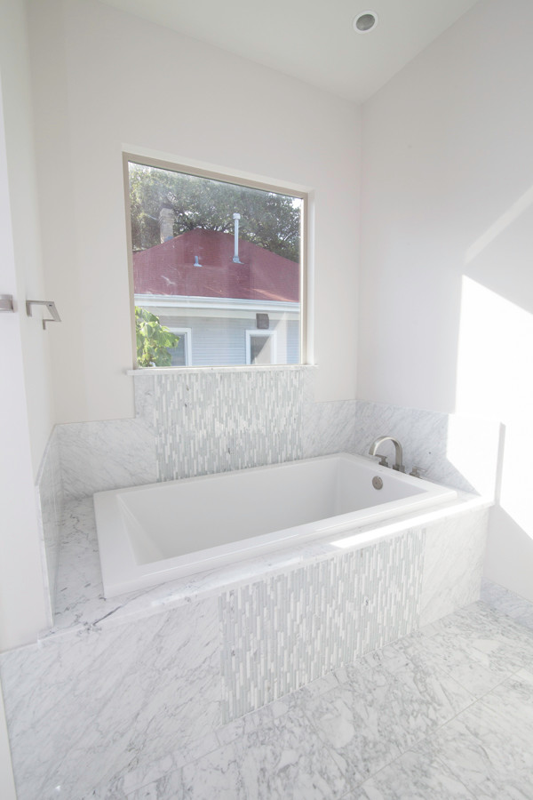 Exempel på ett mellanstort modernt en-suite badrum, med ett platsbyggt badkar, grå kakel, stenkakel, vita väggar och marmorgolv