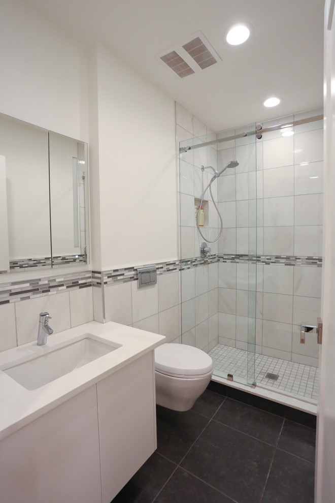 Foto på ett mellanstort funkis badrum med dusch, med släta luckor, vita skåp, en dusch i en alkov, en vägghängd toalettstol, grå kakel, vit kakel, stickkakel, vita väggar, skiffergolv, ett undermonterad handfat och bänkskiva i kvarts