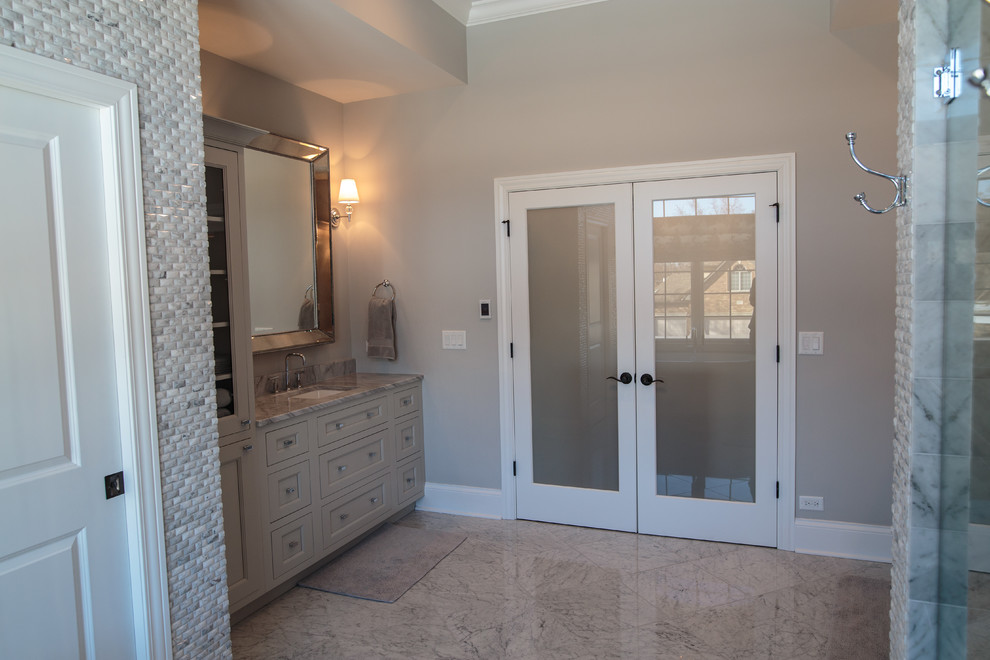 Cette image montre une grande salle de bain principale traditionnelle avec un placard à porte shaker, des portes de placard grises, une baignoire indépendante, un espace douche bain, WC séparés, un carrelage gris, du carrelage en marbre, un mur marron, un sol en marbre, un lavabo encastré et un plan de toilette en marbre.