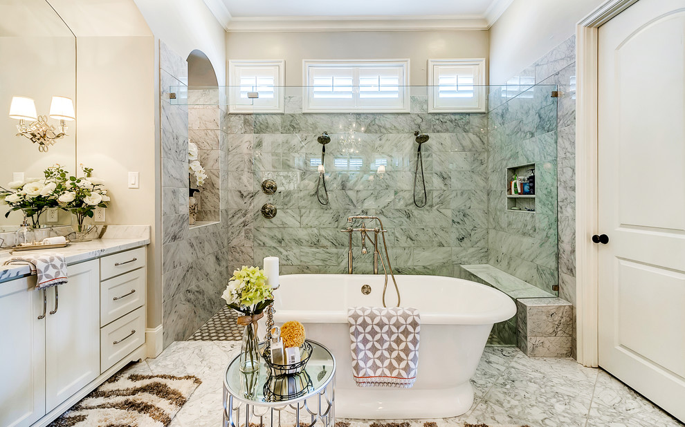 Idée de décoration pour une salle de bain tradition avec un placard à porte shaker, des portes de placard blanches, un plan de toilette en marbre, une baignoire indépendante, une douche double, un carrelage gris, un mur gris et un sol en marbre.