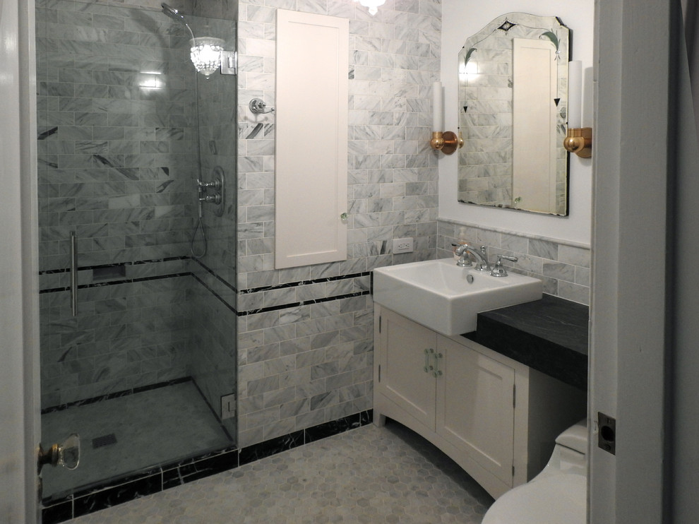 Пример оригинального дизайна: маленькая ванная комната в стиле неоклассика (современная классика) с фасадами в стиле шейкер, белыми фасадами, душем в нише, унитазом-моноблоком, серой плиткой, мраморной плиткой, серыми стенами, мраморным полом, душевой кабиной, накладной раковиной, столешницей из известняка, серым полом, душем с распашными дверями и черной столешницей для на участке и в саду